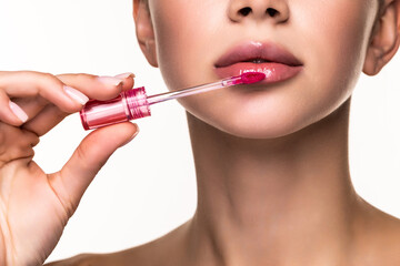 Young woman applying lipstick with an applicator on white background