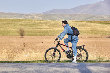 Obraz premium A teenage tourist with a bicycle on the background of the highlands in the fresh air