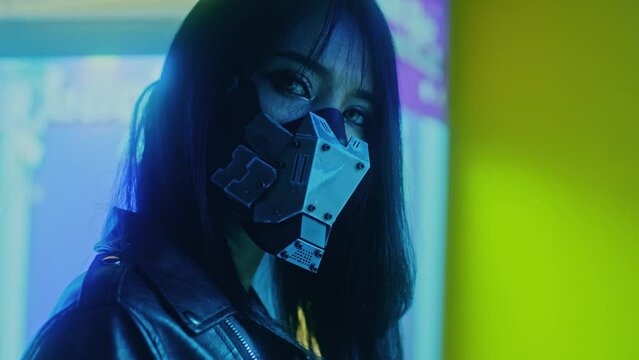 Asian woman wearing a cyberpunk mask amidst the lights stands looking at the camera 