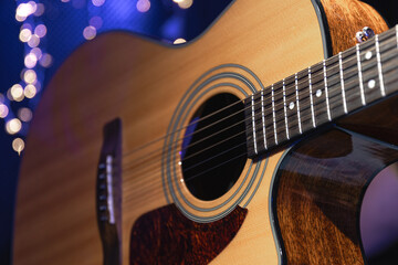 Close-up, acoustic guitar on a dark background with bokeh lights.