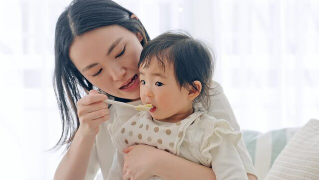 赤ちゃんに離乳食を食べさせるママ