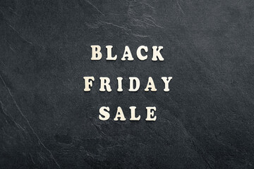 Wooden text Black friday sale on black textured background, top view.