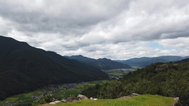 Serene pan across city of asago nestled at base of mountains by japanese ricefields