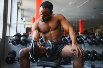 Fototapeta na wymiar Hot african american young man bodybuilder lifting barbell at gym, working on his arms, looking at copy space. Black muscular shirtless guy having biceps workout session. Healthy lifestyle concept.