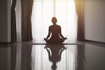 Silhouette of woman Doing yoga at home,  meditation, yoga poses, sport, sunset.  Sports training.