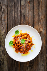 Tagliatelle con ragù alla bolognese - pasta with minced meat and tomato sauce on wooden table