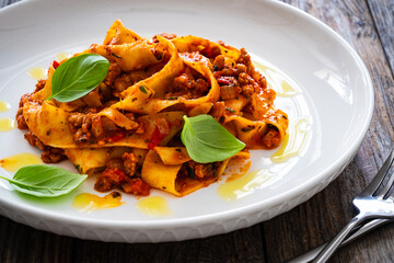 Tagliatelle con ragù alla bolognese - pasta with minced meat and tomato sauce on wooden table