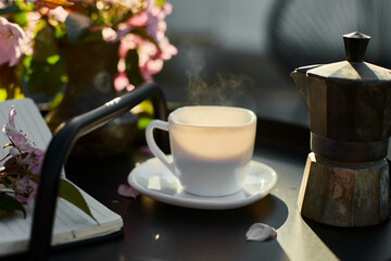 Cup of coffee flowers and notebook on the small black table