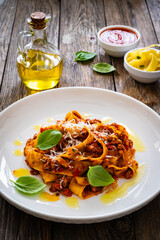 Tagliatelle con ragù alla bolognese - pasta with minced meat and tomato sauce on wooden table