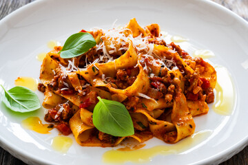 Tagliatelle con ragù alla bolognese - pasta with minced meat and tomato sauce on wooden table