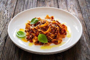 Tagliatelle con ragù alla bolognese - pasta with minced meat and tomato sauce on wooden table