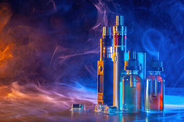 Vape devices in smoke. Electronic cigarettes on table. Small bottles of vaping oil. Vaper gadgets....