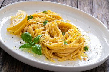 Linguine al limone - pasta with lemon and parmesan on wooden background
