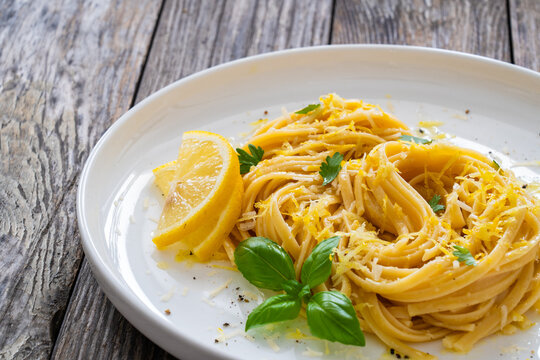 Linguine al limone - pasta with lemon and parmesan on wooden background
