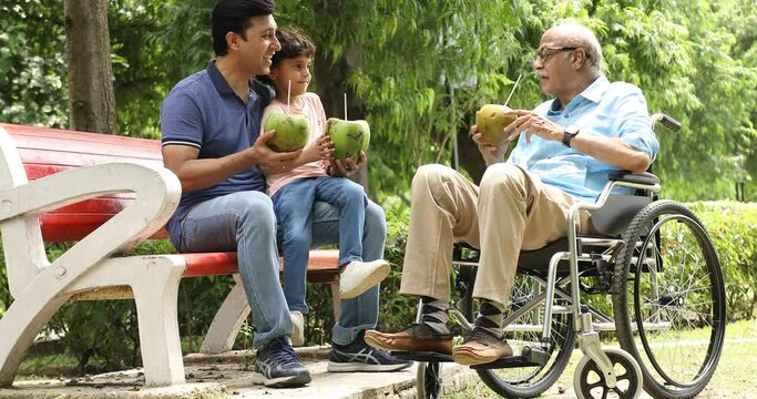 Video of three male generation of family enjoying drinking fresh coconut water in park
