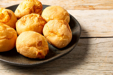brazilian pão de queijo, or cheese breads in a dark plate with copy space