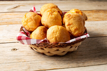 wooden basket with brazilian pão de queijo, or cheese breads in english