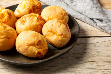 brazilian pão de queijo, or cheese breads in a dark plate, fresh homemade gourmet cheese buns