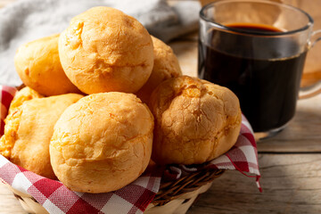 basket with pão de queijo or cheese buns, cheese bread in a wooden table with black coffee