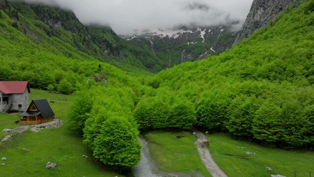 Evening time in mountain village in green valley, clouds over the mountain peak. establishing drone shot
