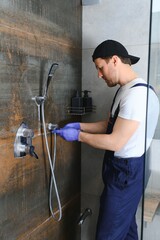 Professional handyman working in shower booth indoors