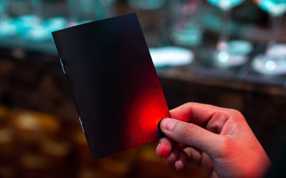 Hand holding a blank cover of book with red and blue neon light. Mock Up Template. Nightlife concept.
