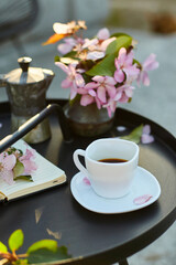 Cup of coffee flowers and notebook on the small black table