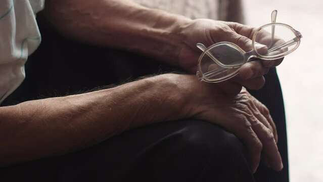 close-up in the hands of a sitting pensioner, vintage glasses are old, being inside the deterioration of vision in old age. senile farsightedness and astigmatism.