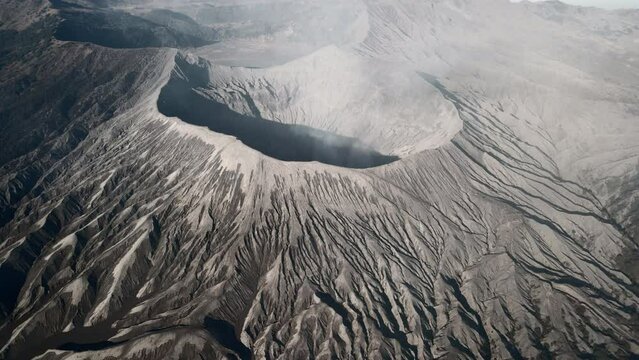 Mount Bromo active volcano landscape. Aerial orbit rotation looking into the volcanic smoking crater of this desert lifeless baron moon like surface.