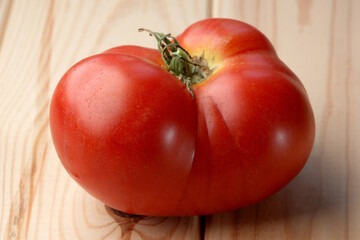 Red ripe sweet tomato on a wooden light table