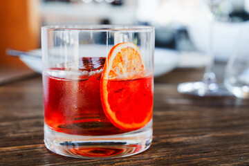 Negroni cocktail in old fashion glass with orange slice on wooden table. Classic negroni cocktail with an orange slice on table.