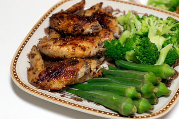 Keto lunch grilled chicken buffalo wings with vegetables okra and broccoli. 