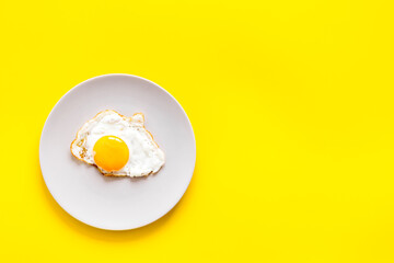 Fast breakfast with one fried egg on plate, top view