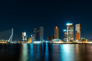 Naklejka premium Immersed in the Timeless Beauty of Rotterdam's Nightfall, Where Skyscrapers Sparkle Amidst Reflections on the Water