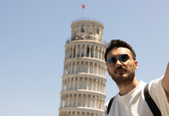 Young tourist man taking selfie with pisa tower in Italy. 