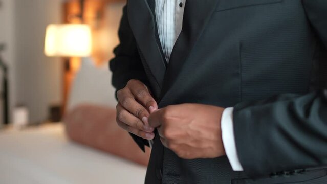 Groom buttoning his suit, getting dressed in the room. Preparations for the wedding.