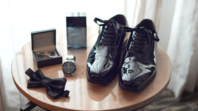 Preparations for the wedding. Table with shoes, watch, perfume, bow tie and cufflinks of the groom.