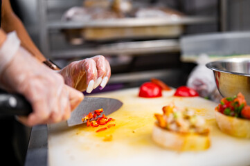 chef hand Cutting red chili pepper on the cutting board in kitchen