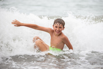 Cheerful happy child plays with sea waves, smiles.