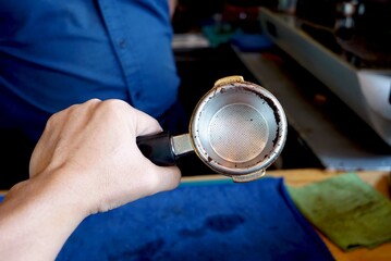 Hand of a barista in a blue shirt with a coffee filter to checking.