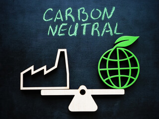 Symbolic scales with an industrial plant and green planet. Carbon neutral concept.