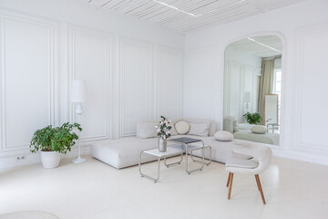 interior of a bright living room in a luxurious baroque style with white walls decorated with antique stucco