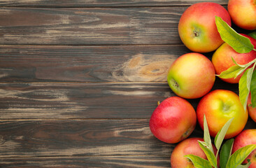 Group of red apples with their leaves on brown background. Space for text