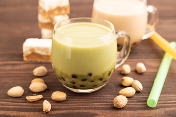 Bubble tea with pistachio and caramel in glass on brown wooden, Side view, selective focus.