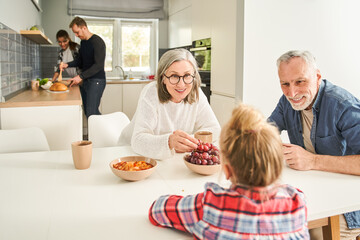 Cute grandmother and grandfather talking with little girl during the breakfast