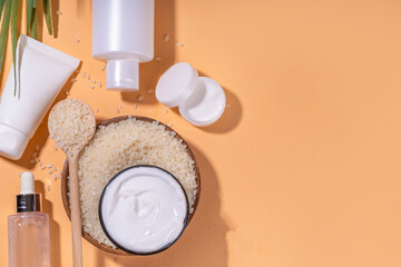 Rice Water organic cosmetics, beauty skin care. Natural fermented rice cream, serum, body treatment, shampoo, conditioner  bottles with rice grain and bath utensils copy space