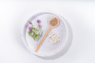 Fototapeta na wymiar Milk Thistle supplies, powder and oil. Silybum marianum, natural organic wild flower superfood product - whole and grain seeds, pills, oil with fresh thistle flowers