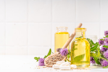Milk Thistle supplies, powder and oil. Silybum marianum, natural organic wild flower superfood product - whole and grain seeds, pills, oil with fresh thistle flowers