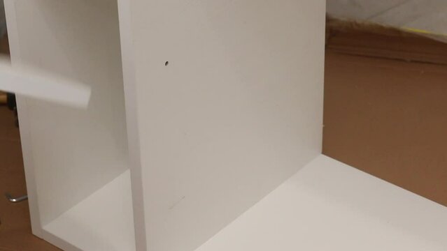 A man assembles a bookshelf on his own. Installs shelves on holders. Close-up