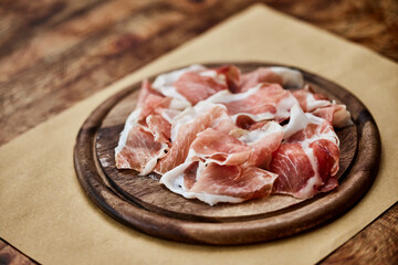 The appetizer at the restaurant, ham served on the wooden board.